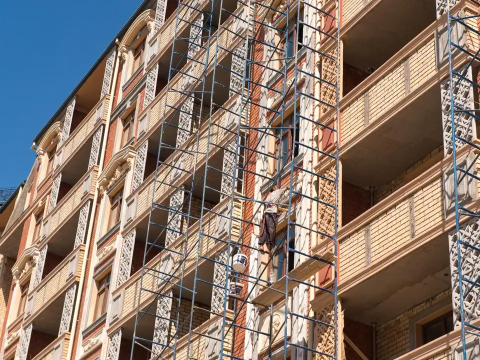 Façade d'un immeuble d'habitation en briques couverte d'échafaudages pendant des travaux de ravalement